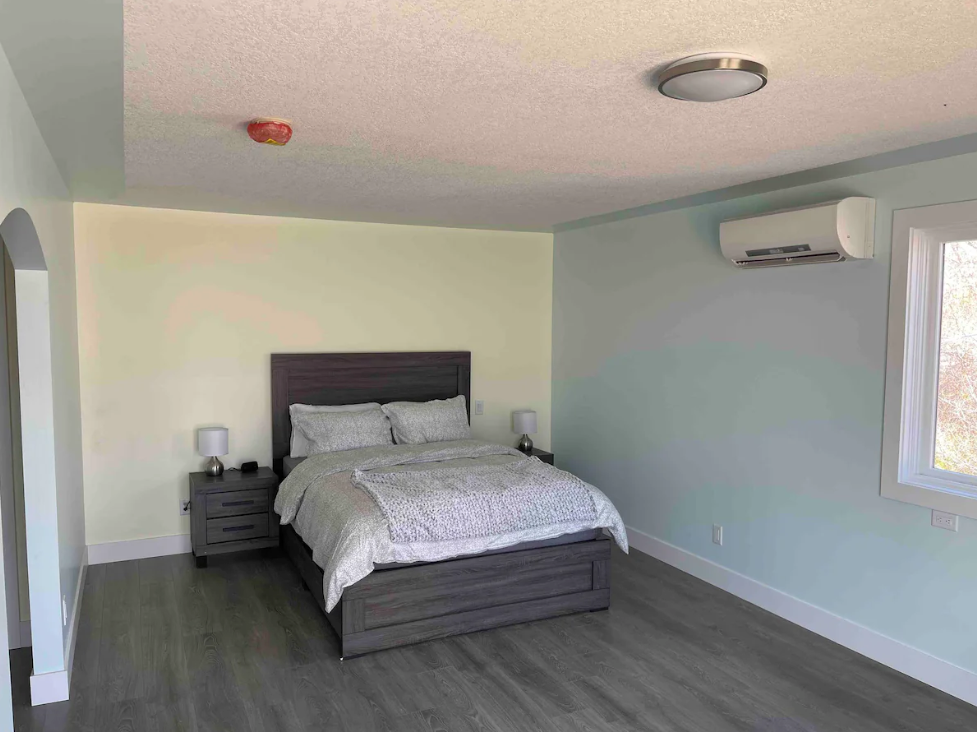 Spacious bedroom with a large bed, nightstands, and an air conditioner on the wall.