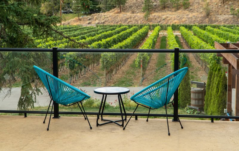 Relaxing outdoor seating with two blue chairs overlooking a lush vineyard landscape.