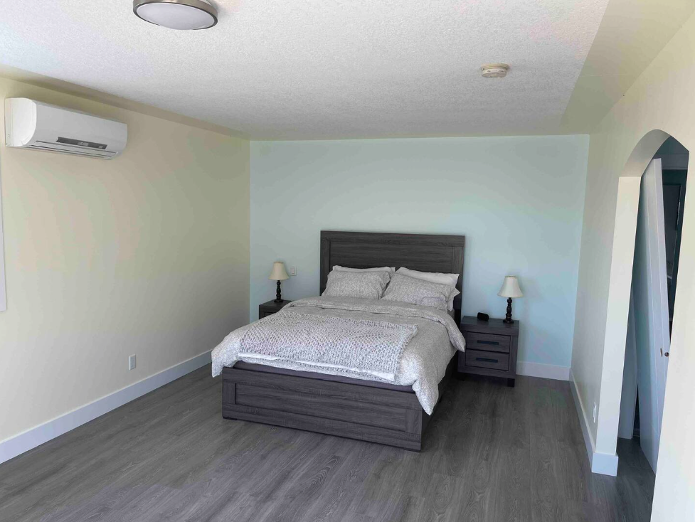 Spacious bedroom with a large bed, nightstands, and air conditioning in a modern accommodation setting.