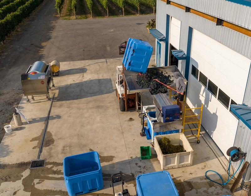 Aerial view of an industrial waste management area with blue containers, equipment, and a warehouse building.